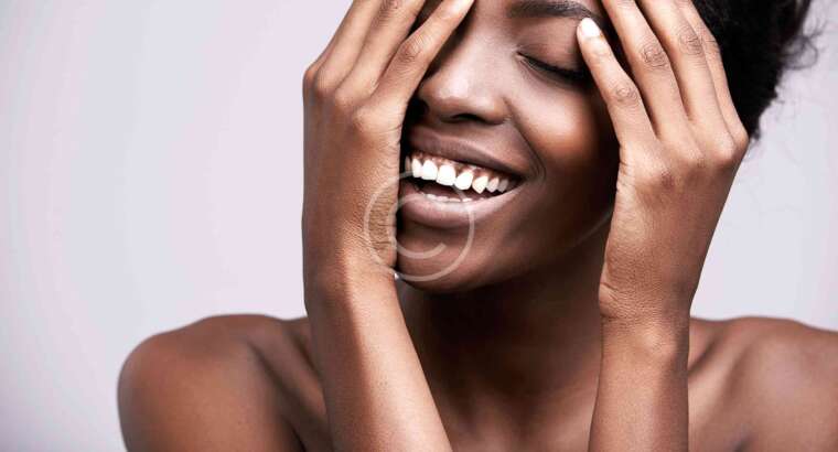 Smiling woman covering face with hands.